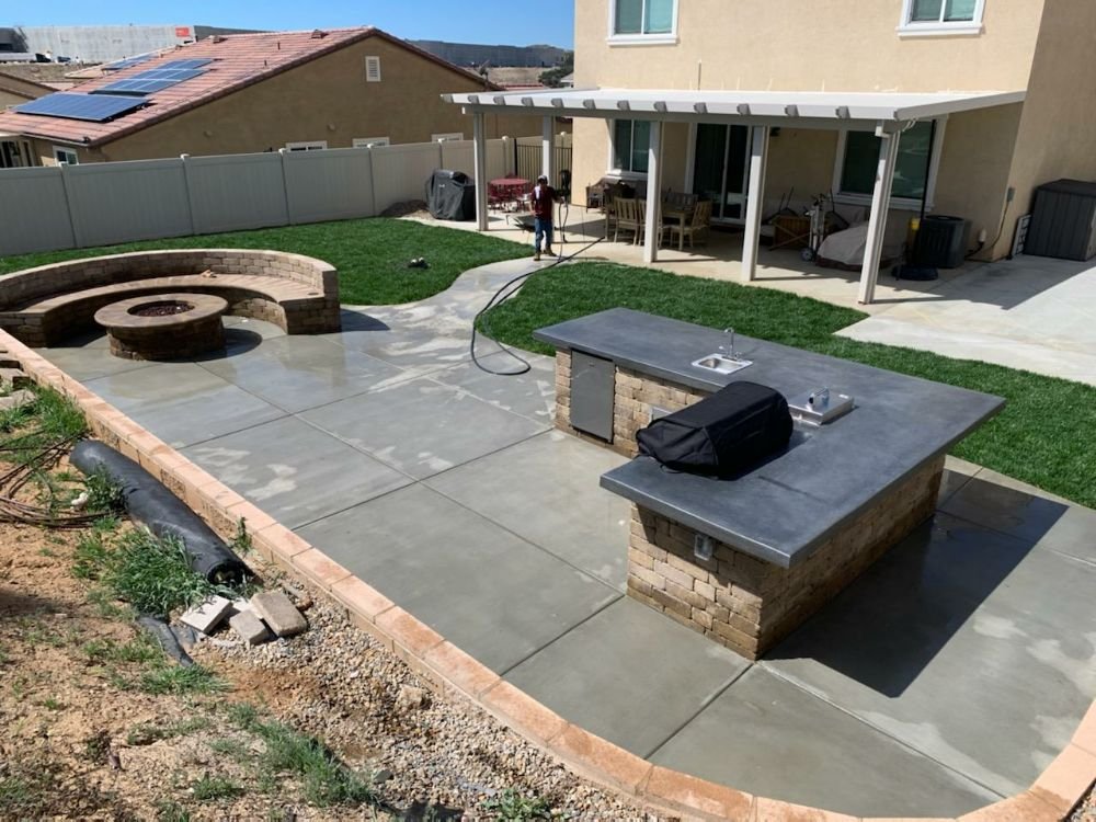 Redesigned backyard with firepit seating, outdoor island, and lawn