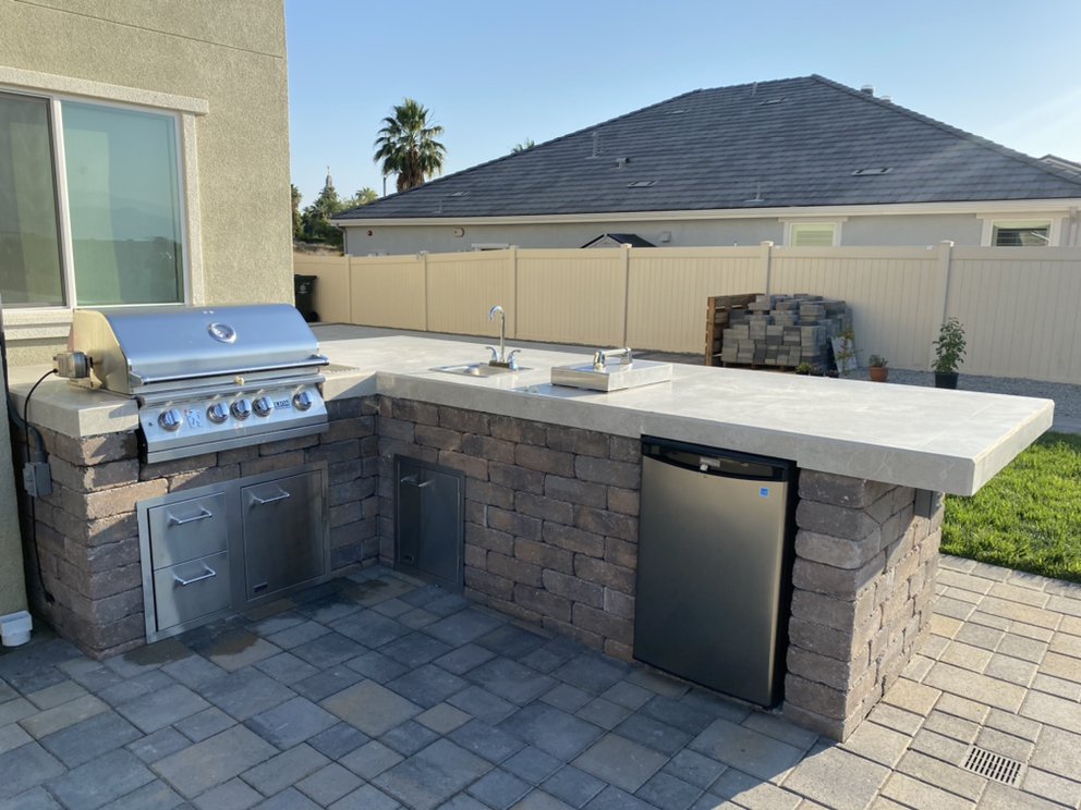 Outdoor kitchen island with grill, sink, and refrigerator